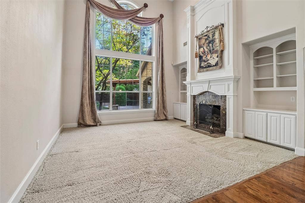 2600 Saratoga, McKinney, TX 75070 Two-story windows, vaulted ceiling, built-in shelving, fireplace with stone surround, and wood-finish flooring