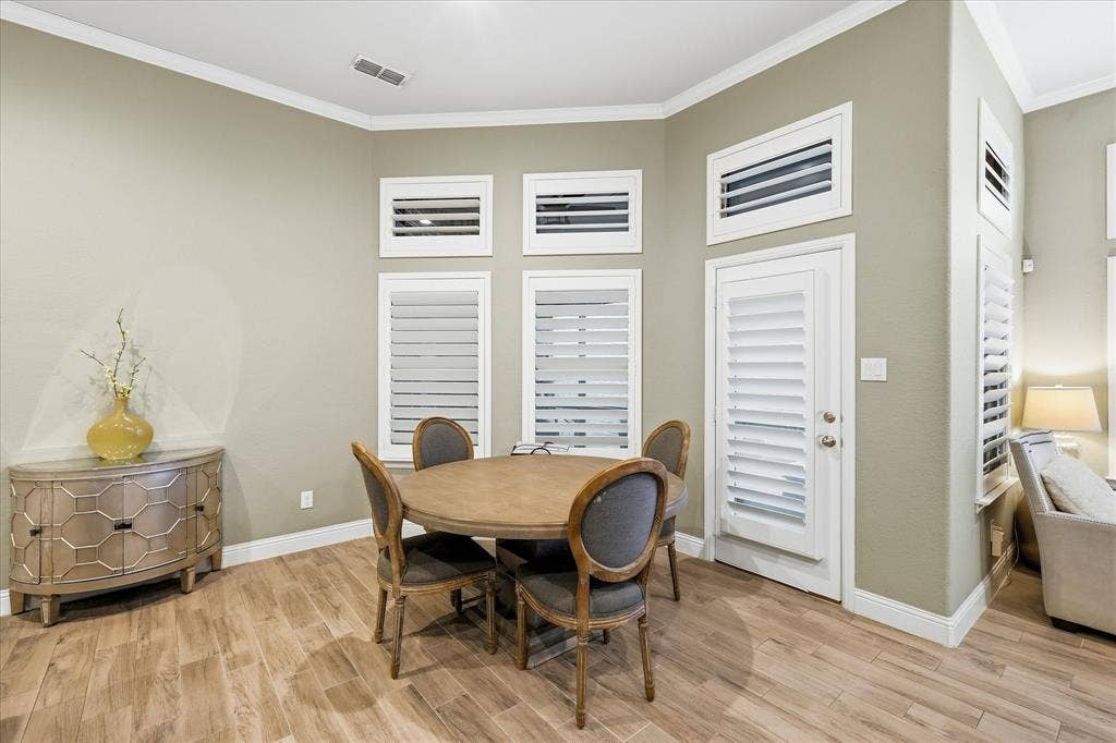 904 10th Street, Argyle, TX 76226 Dining area featuring wood-finish flooring, light-toned walls, crown molding, and multiple windows with plantation shutters