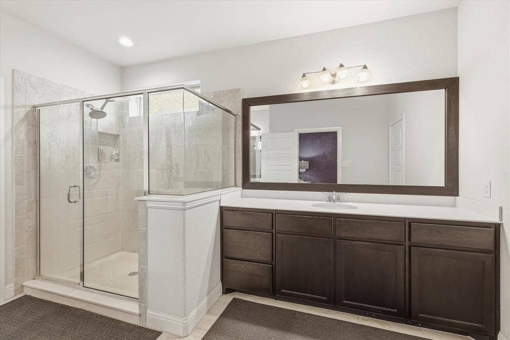 904 10th Street, Argyle, TX 76226 Spacious bathroom featuring a glass-enclosed shower with tile surround, a built-in shower niche, and a rain shower head