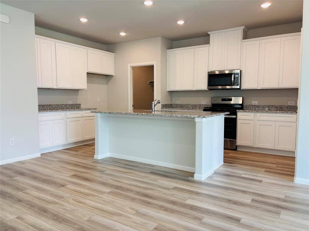 912 Santa Lucia Drive, Anna, TX 75409 Kitchen featuring stainless steel appliances, light wood-type flooring, recessed lighting, an island with sink, and light stone countertops