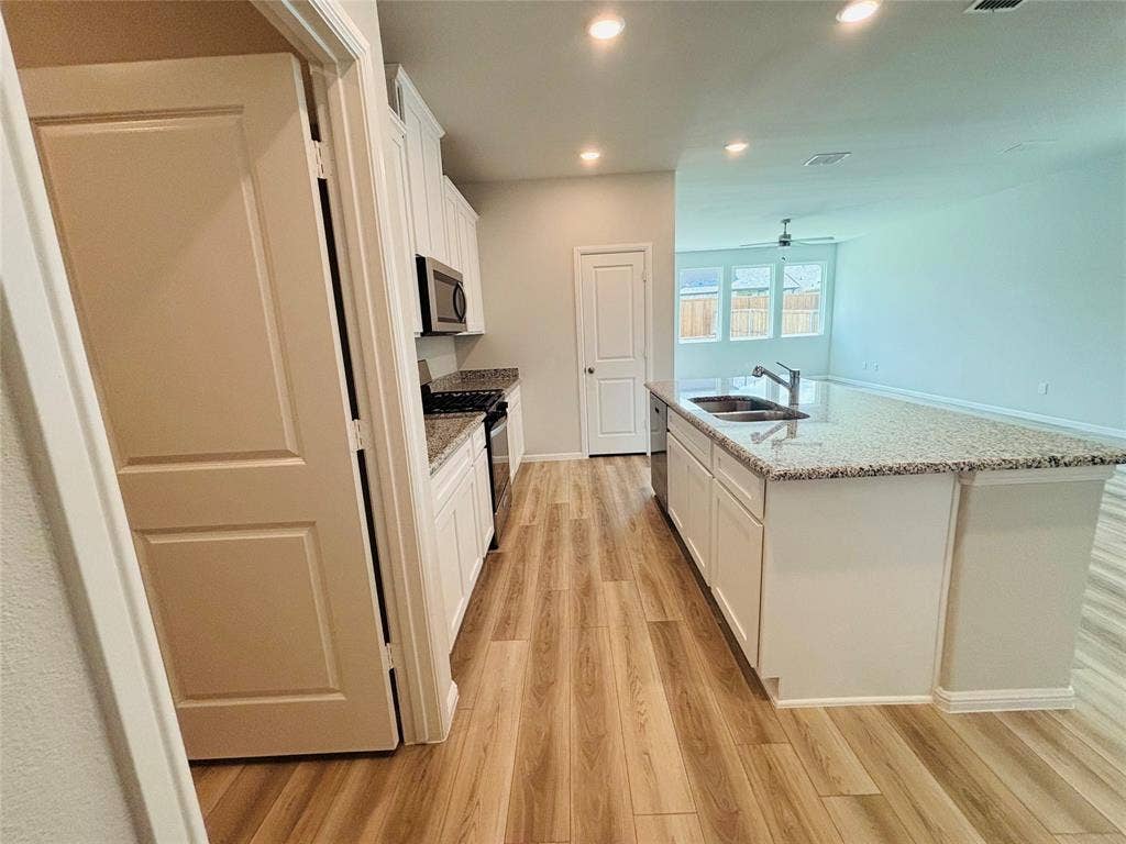 912 Santa Lucia Drive, Anna, TX 75409 Kitchen with appliances with stainless steel finishes, light wood-style floors, white cabinetry, recessed lighting, and a center island with sink