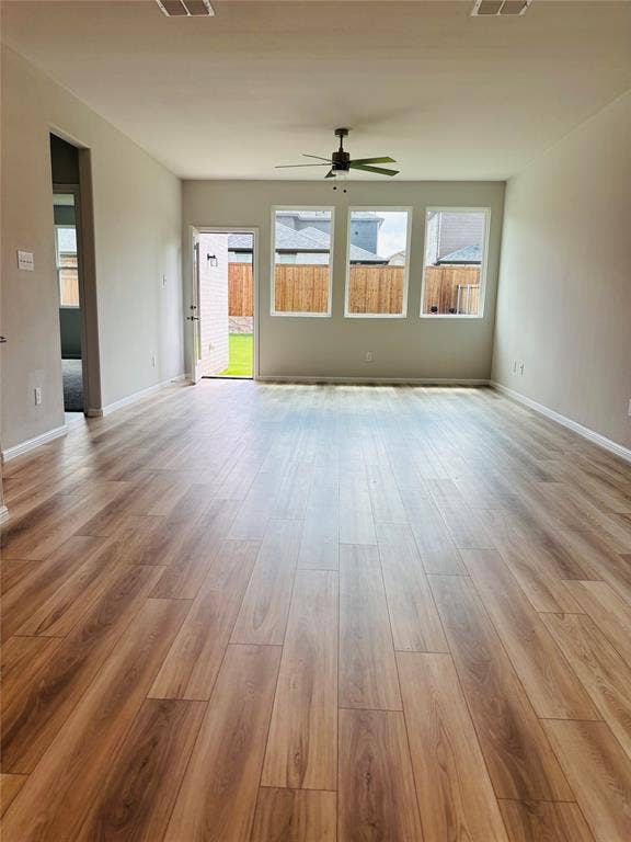 912 Santa Lucia Drive, Anna, TX 75409 Unfurnished living room featuring a ceiling fan, plenty of natural light, and wood finished floors