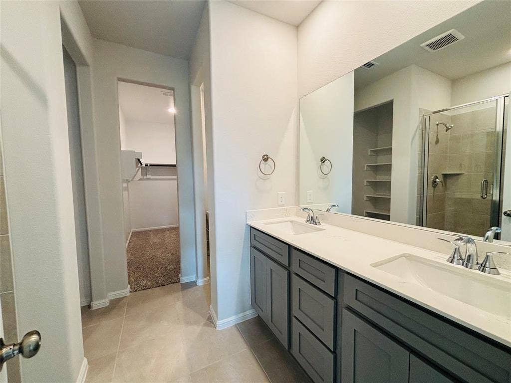 912 Santa Lucia Drive, Anna, TX 75409 Bathroom featuring a walk in closet, double vanity, a stall shower, and tile patterned flooring