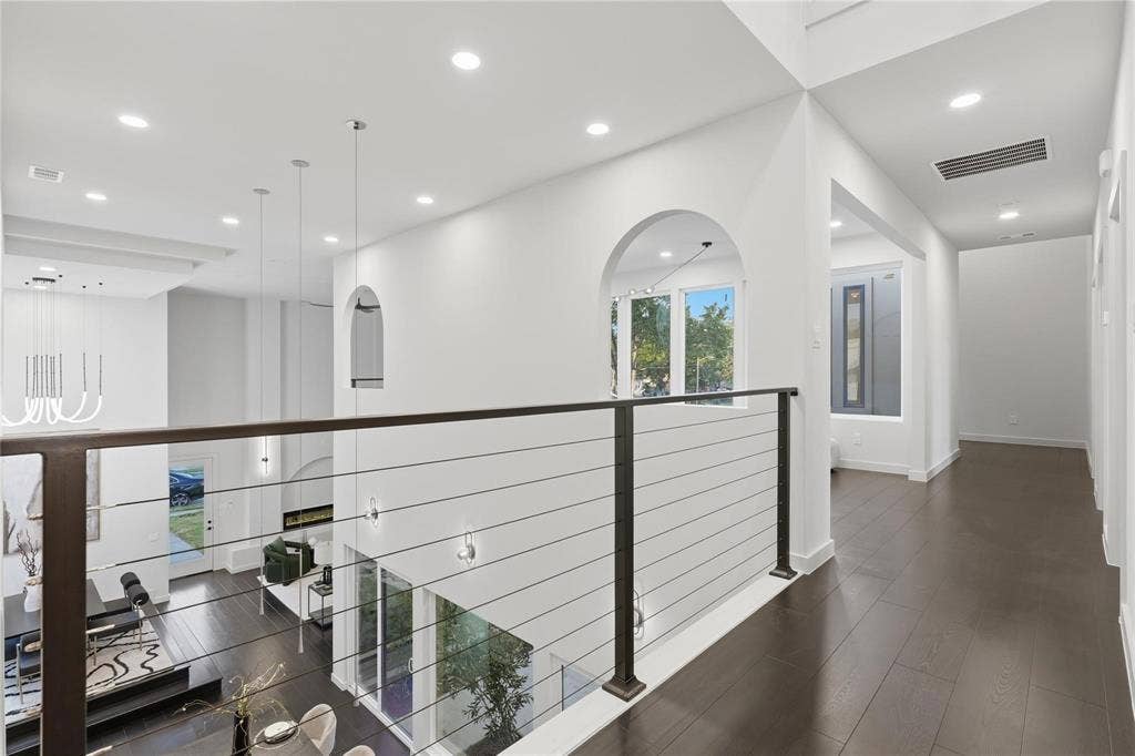 Upper-level hallway featuring dark wood-finish flooring, recessed lighting, and a contemporary cable railing system