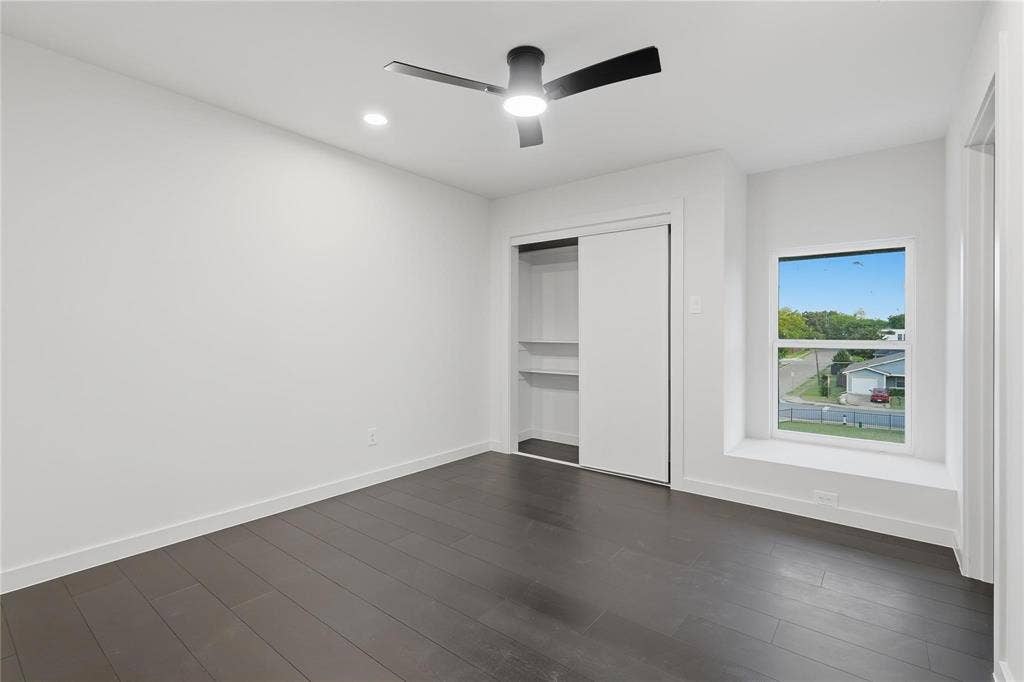 Spacious room featuring dark wood-finish flooring, a contemporary ceiling fan with integrated lighting, recessed lighting, and a white sliding door closet with built-in shelving