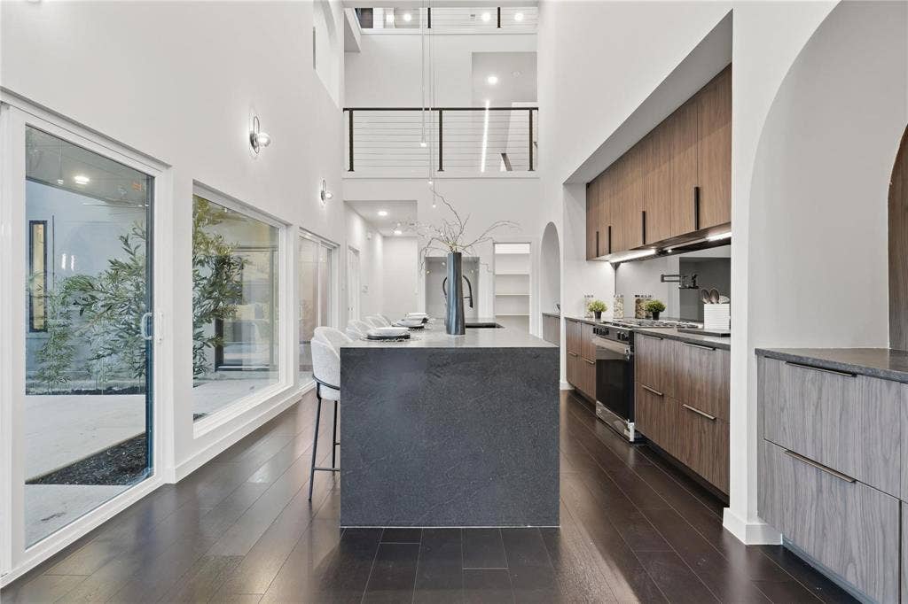 Modern kitchen with dark wood-finish flooring, a waterfall island, and integrated stainless steel appliances