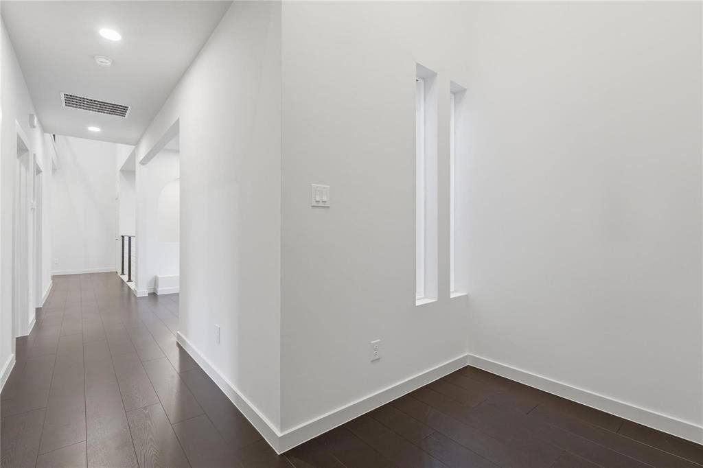 Hallway featuring dark wood-finish flooring, recessed lighting, and white baseboards