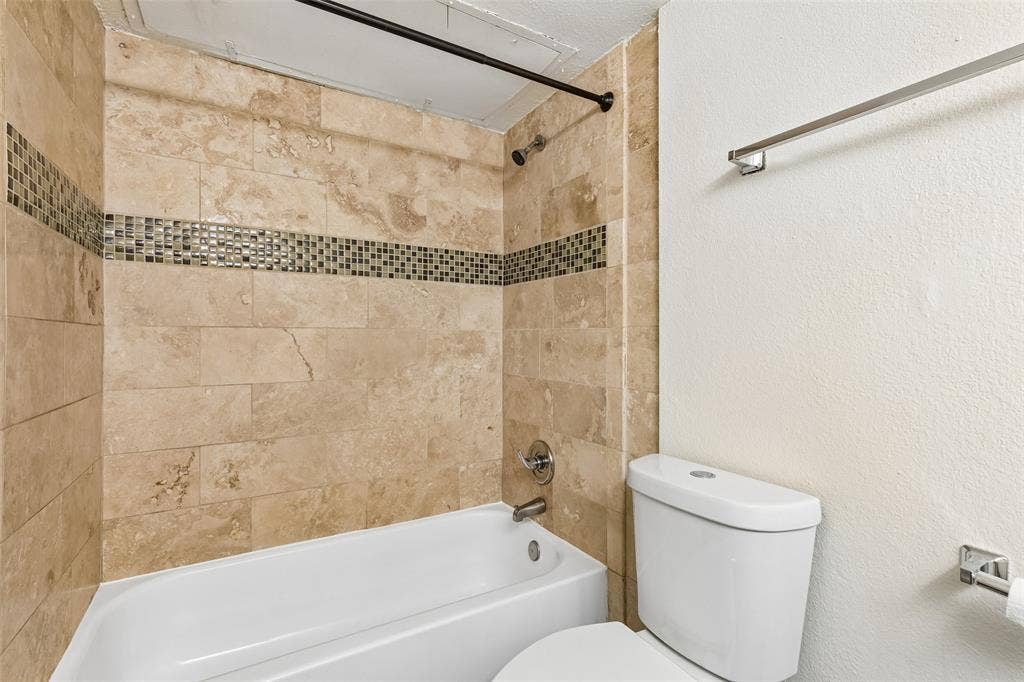 6108 Abrams Road, #610, Dallas, TX 75231 Bathtub with stone-finish tile surround and decorative mosaic accent band