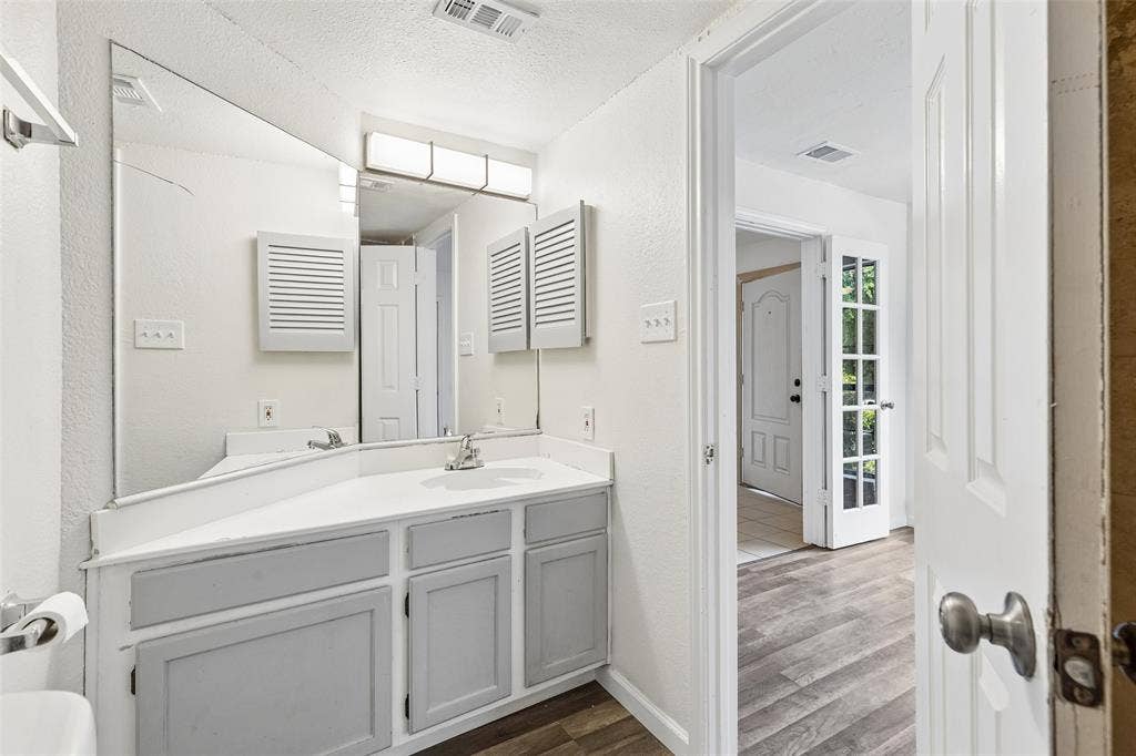 6108 Abrams Road, #610, Dallas, TX 75231 Bathroom vanity featuring a single basin sink, white countertop, and gray wood-finish cabinetry