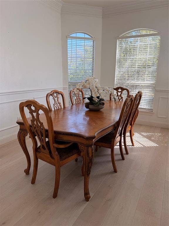 2301 Clearspring Drive S, Irving, TX 75063 Bright dining area featuring light wood-finish flooring, white wall paneling, and two arched windows with blinds