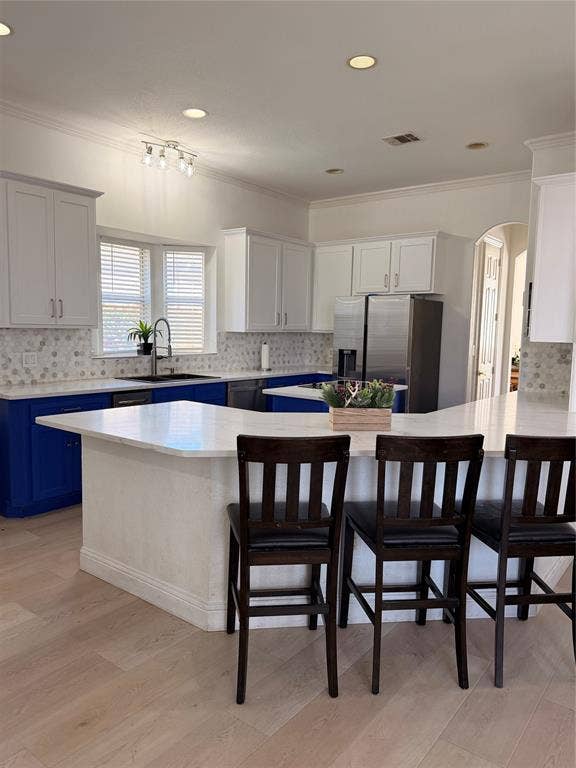 2301 Clearspring Drive S, Irving, TX 75063 Kitchen featuring light wood-finish flooring, white perimeter cabinetry, blue island cabinetry, and a light-toned countertop