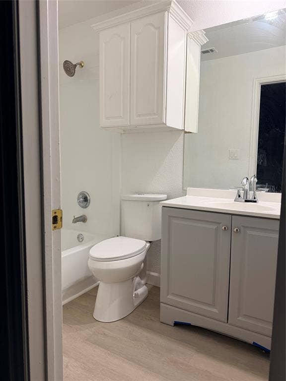 2301 Clearspring Drive S, Irving, TX 75063 Bathroom featuring a white tub and shower combination with a decorative showerhead, a white toilet, a white upper cabinet with crown molding, a vanity with gray shaker-style doors, and wood-finish flooring