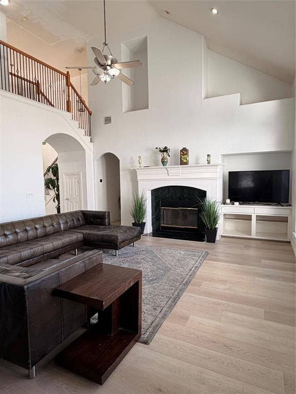 2301 Clearspring Drive S, Irving, TX 75063 Spacious living area featuring a two-story ceiling, light wood-finish flooring, and a fireplace with a white mantel and dark stone surround