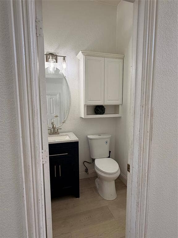 2301 Clearspring Drive S, Irving, TX 75063 Powder room featuring a dark wood-finish vanity with a light-toned countertop, a contemporary oval mirror, and a sleek two-light vanity fixture