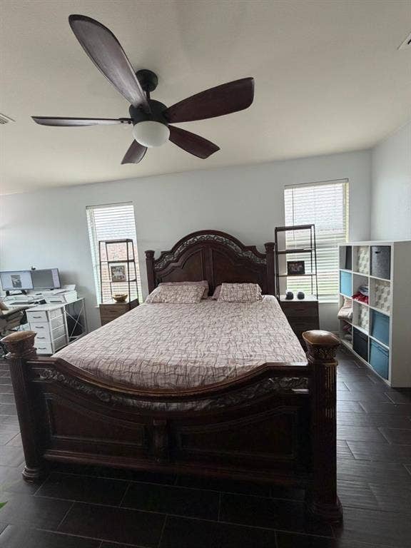 Spacious room featuring dark wood-finish flooring, two large windows with blinds, and white painted walls