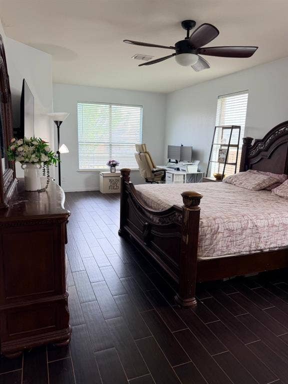 Spacious interior featuring dark wood-finish flooring, a ceiling fan with integrated lighting, and multiple windows with horizontal blinds