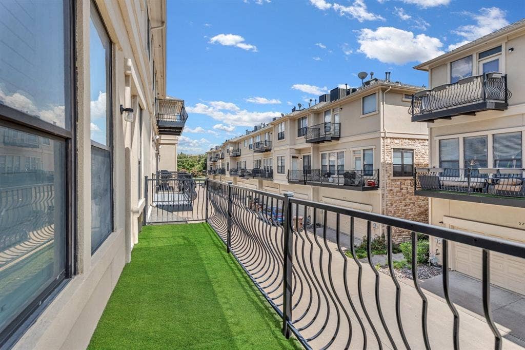 Balcony featuring artificial turf flooring and ornate wrought iron railings