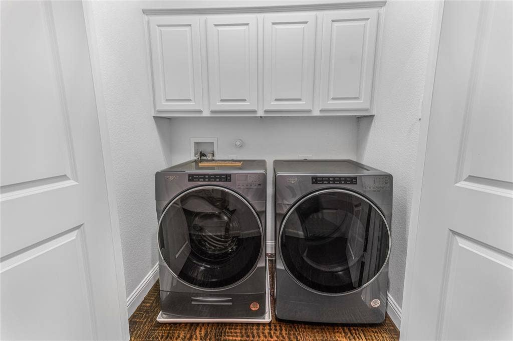 Dedicated laundry area featuring overhead white cabinetry, wood-finish flooring, and white interior doors