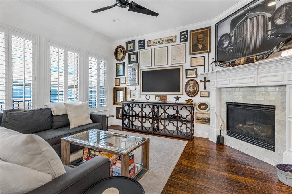 Living room featuring rich wood-finish flooring and a corner fireplace with a tiled surround and white mantel