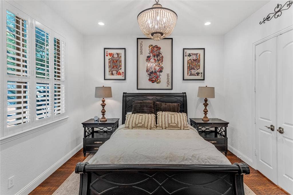 Bedroom featuring hardwood-finish flooring, white walls, and a beaded chandelier
