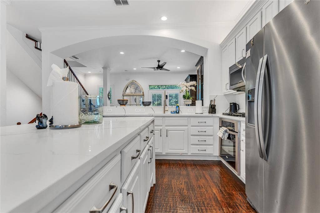 Kitchen featuring white shaker cabinetry, stainless steel appliances, light-toned countertops, and wood-finish flooring