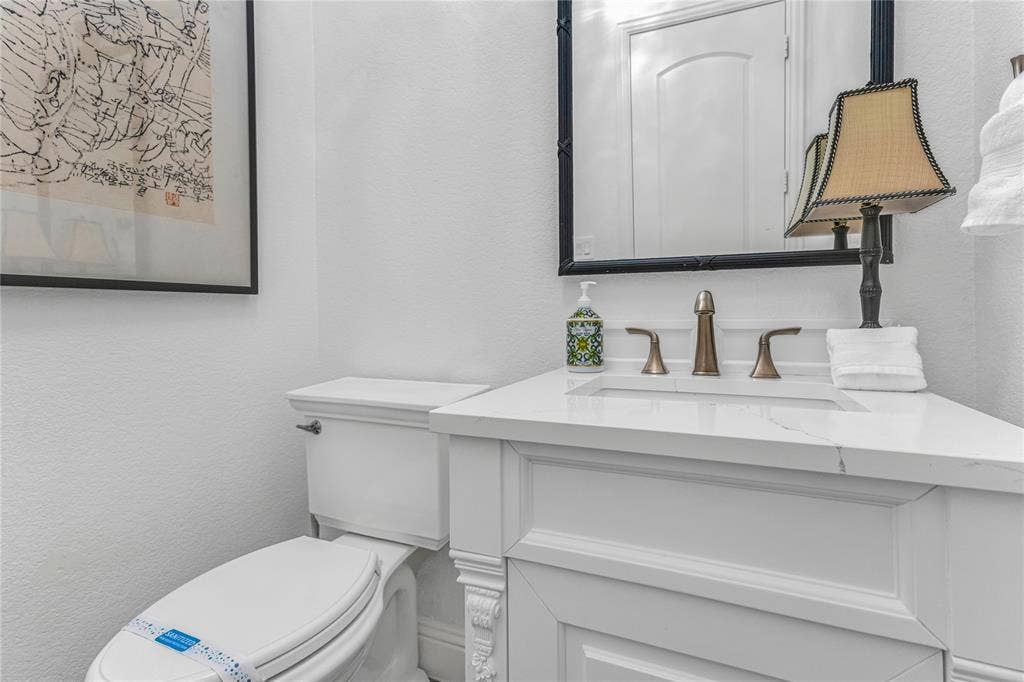 White vanity with a rectangular undermount sink, quartz countertop, and bronze-finish faucet