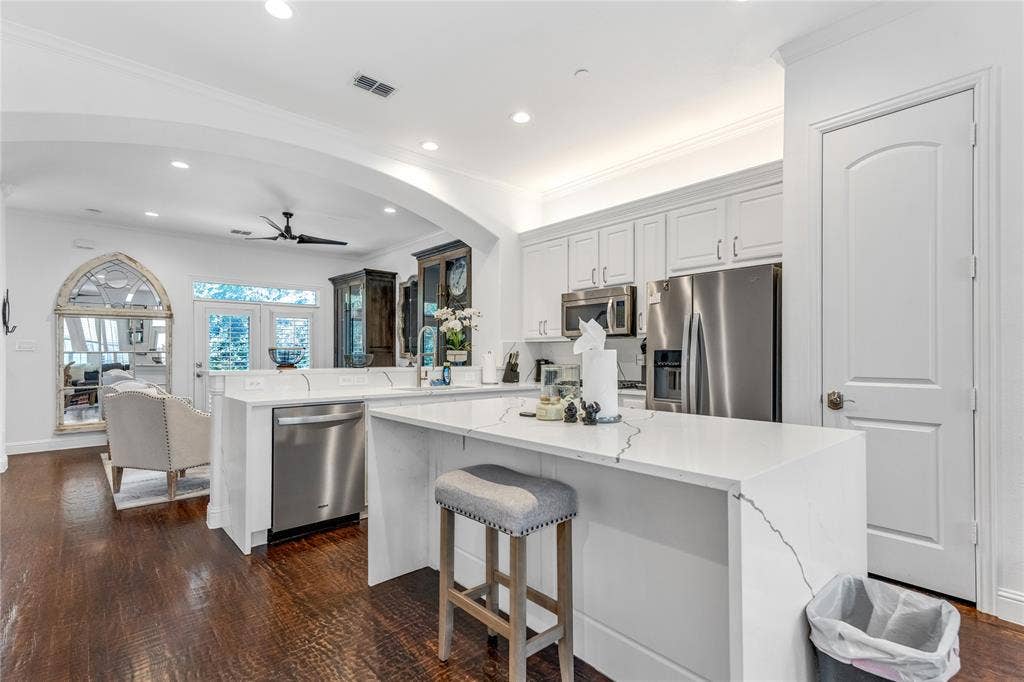 Open-concept kitchen with white cabinetry and stainless steel appliances
