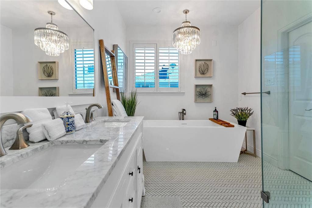 Bathroom featuring a dual vanity with a stone countertop, a freestanding soaking tub, and a separate glass-enclosed shower