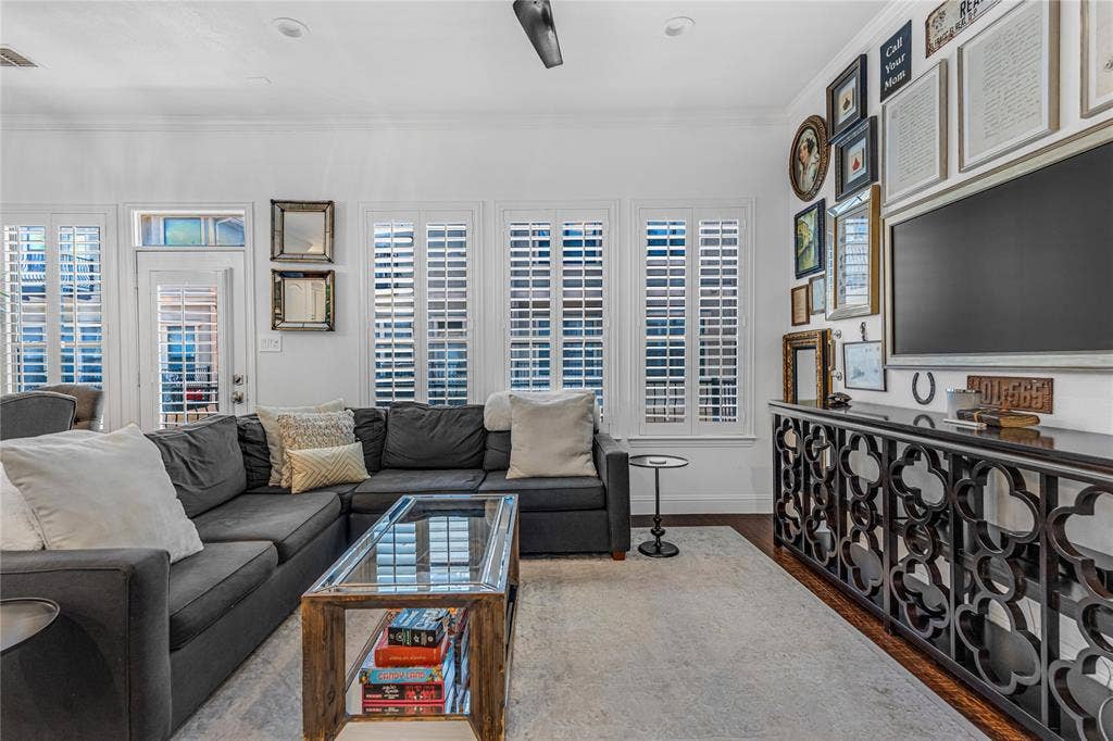 Living area featuring wood-finish flooring, white plantation shutters, recessed lighting, and a ceiling fan