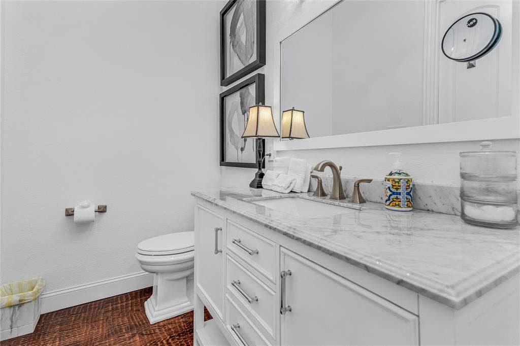 White vanity with a marble countertop, undermount sink, and brushed nickel faucet