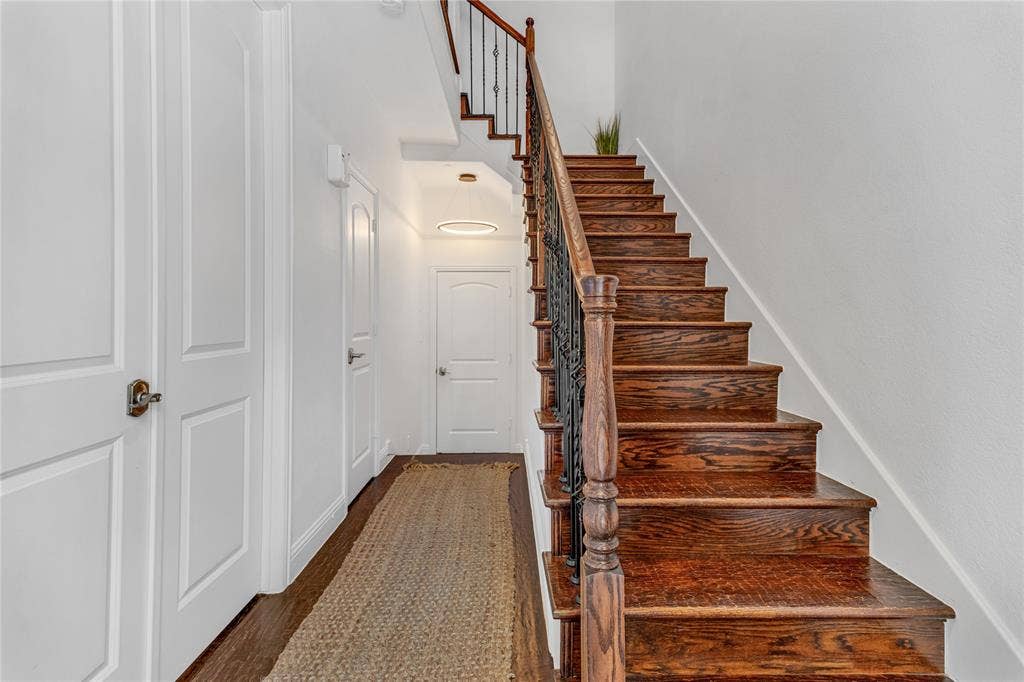 Hardwood staircase with wrought iron balusters and a dark wood handrail