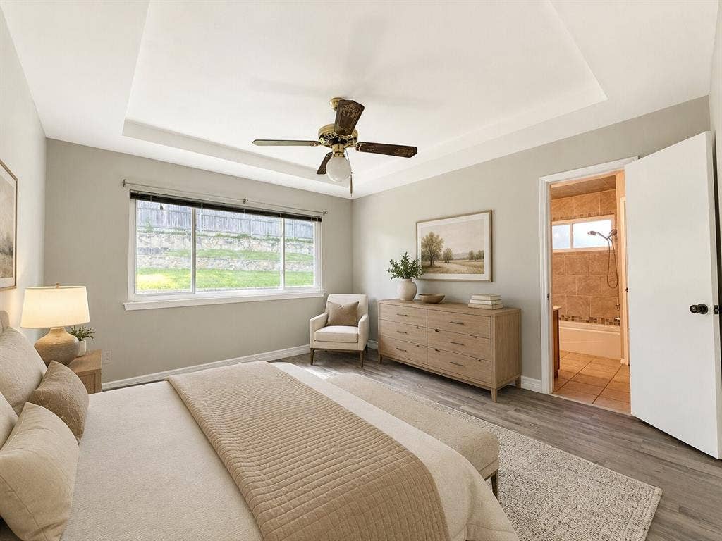 601 Ascot Drive, Euless, TX 76040 Bedroom featuring a tray ceiling with a ceiling fan, wood-finish flooring, and a large window