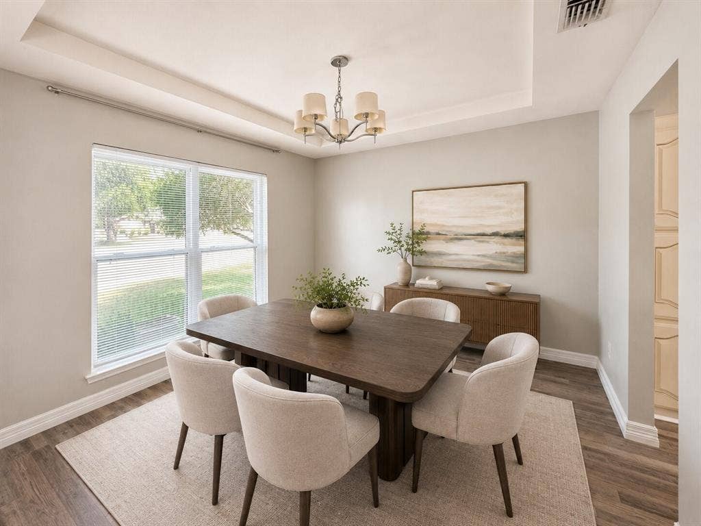 601 Ascot Drive, Euless, TX 76040 Tray ceiling with a decorative chandelier, large window with blinds, wood-finish flooring, and light-toned walls