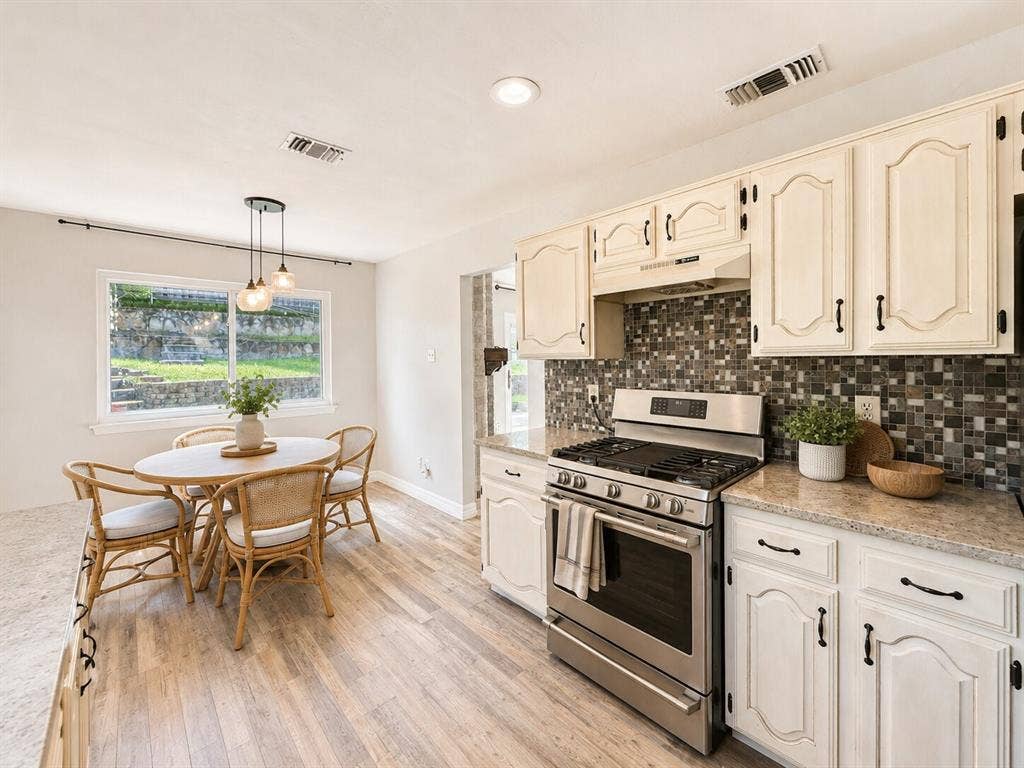 601 Ascot Drive, Euless, TX 76040 Kitchen featuring light cabinetry with dark hardware, stainless steel range, mosaic tile backsplash, and light-toned countertops