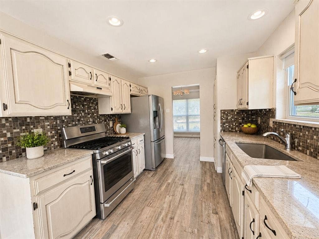 601 Ascot Drive, Euless, TX 76040 Kitchen featuring light-toned cabinetry with dark hardware, granite countertops, and a mosaic tile backsplash