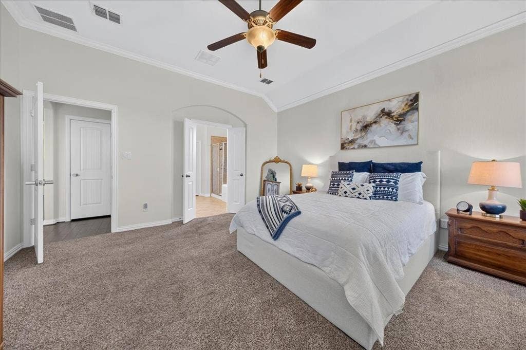 Vaulted ceiling with crown molding, ceiling fan, and carpeted flooring