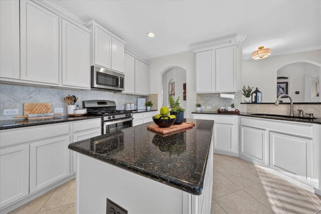 White shaker-style cabinetry, dark speckled countertops, stainless steel appliances, and a diagonal tile backsplash