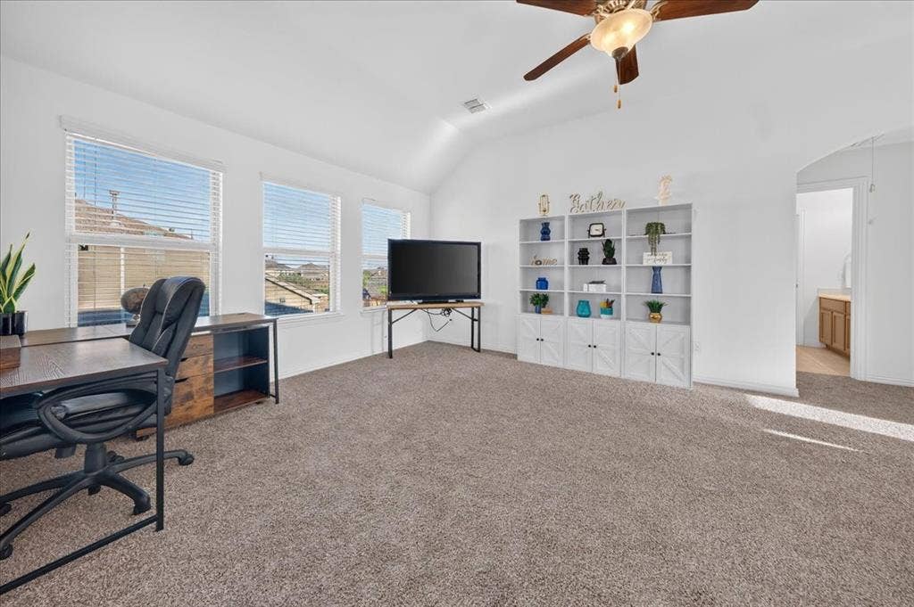 Vaulted ceiling with a ceiling fan, multiple windows with blinds, and carpet flooring