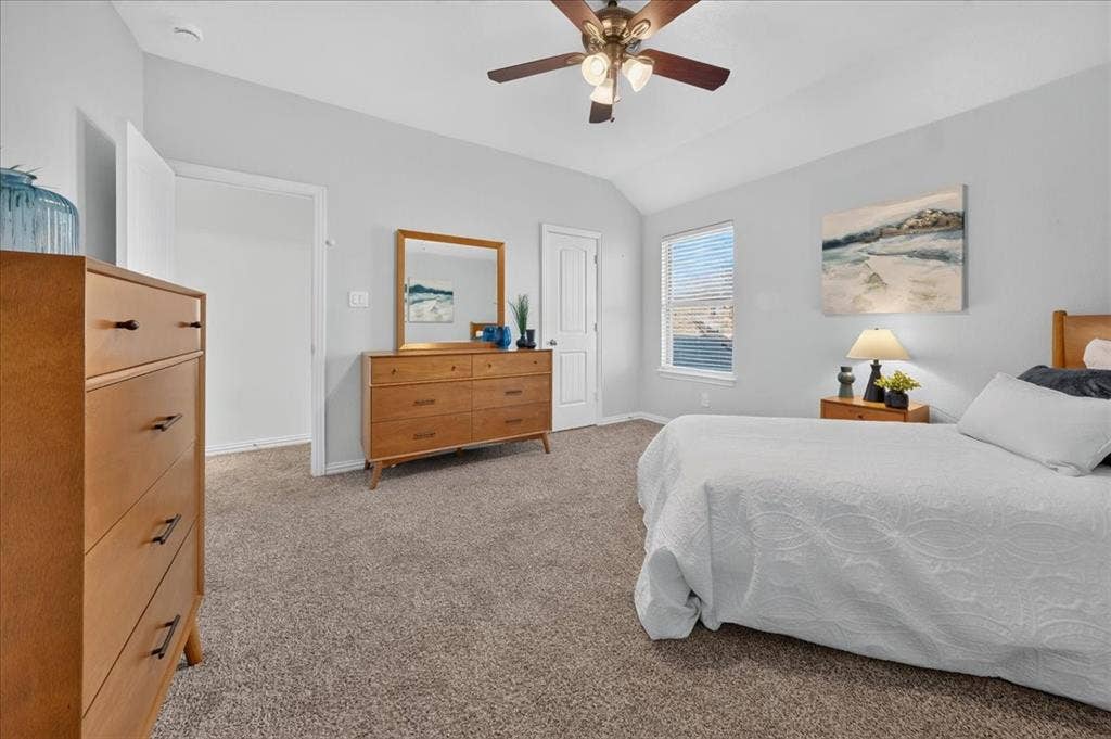 Vaulted ceiling with a ceiling fan, light-colored carpet, large window with blinds, and white interior doors