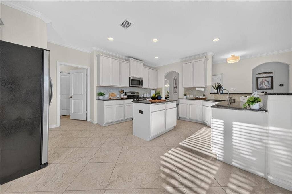 Kitchen featuring white cabinetry, dark countertops, a central island, recessed lighting, and tile flooring