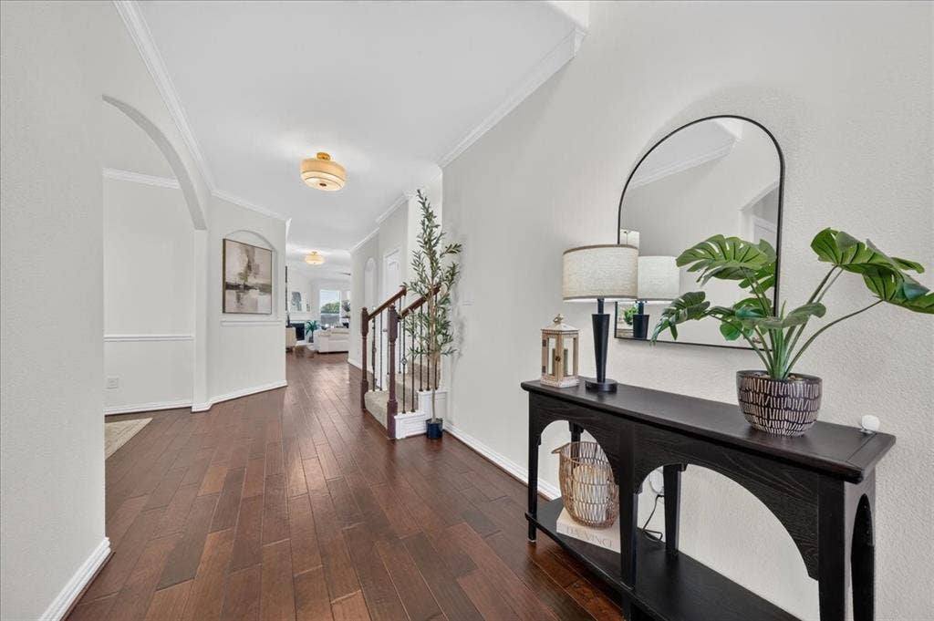 Elegant foyer showcasing rich wood-finish flooring, white shaker-style wall paneling, and a coffered ceiling with recessed lighting