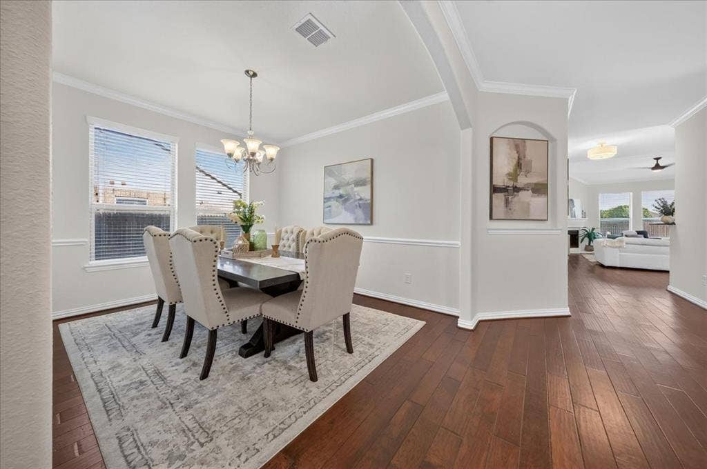 Wood-finish flooring, crown molding, chair rail, and multiple windows with blinds