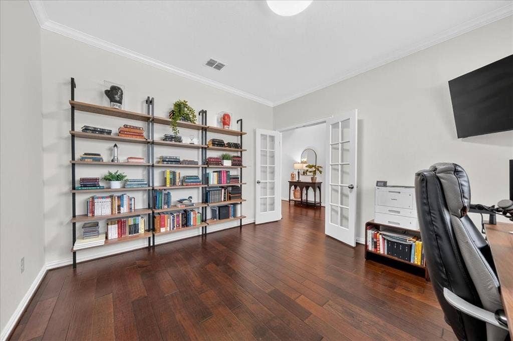 Hardwood flooring, crown molding, built-in shelving, and French doors