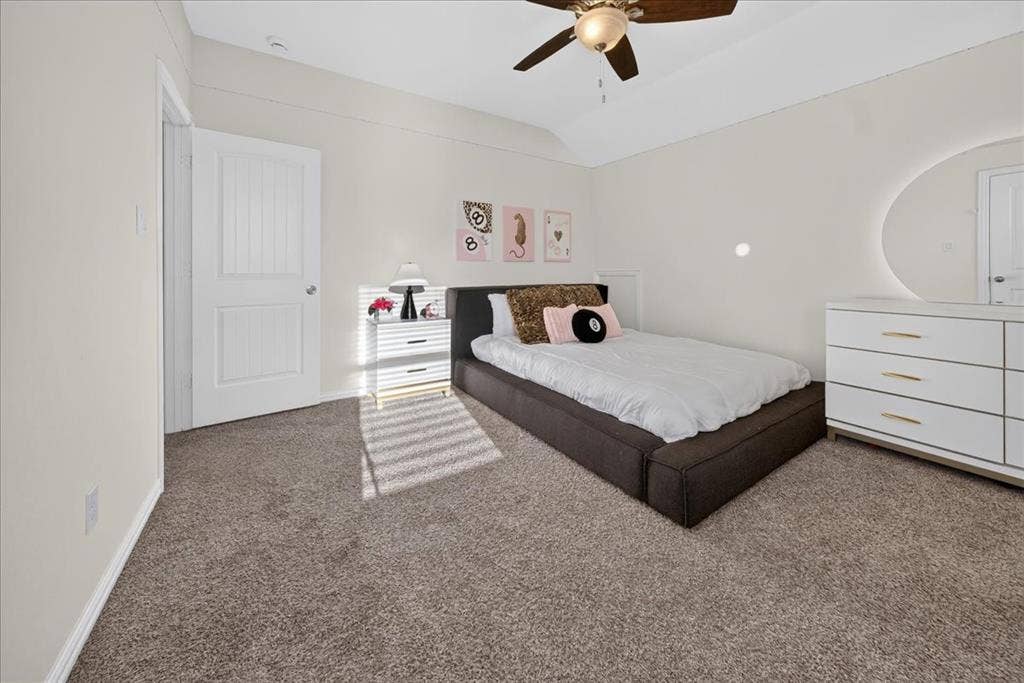 Ceiling fan with light fixture, white interior door, light-colored walls, and carpeting