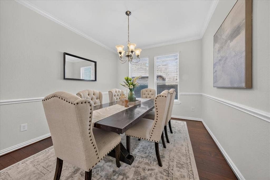 Dining area with wood-finish flooring, crown molding, and chair rail detailing