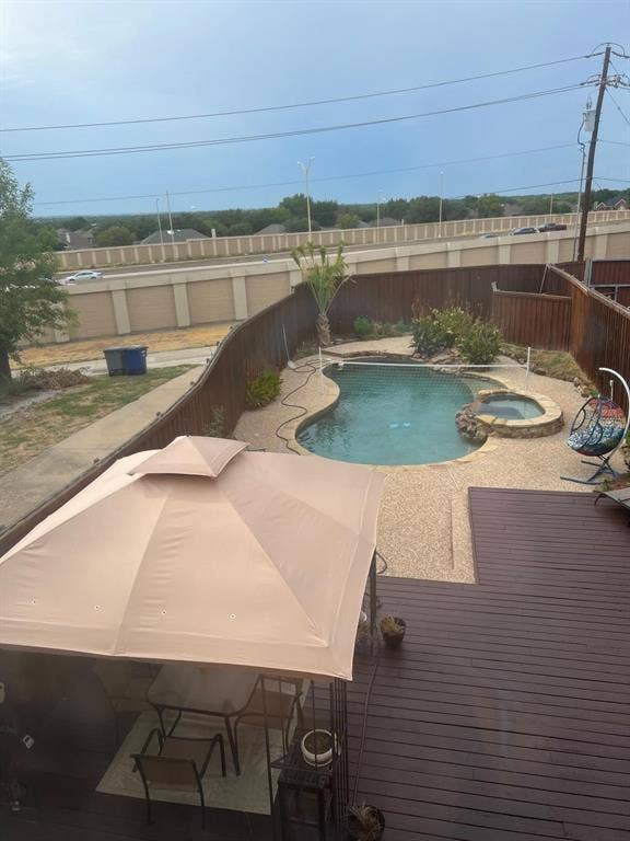 Backyard oasis featuring a freeform swimming pool, integrated hot tub, and exposed aggregate concrete decking