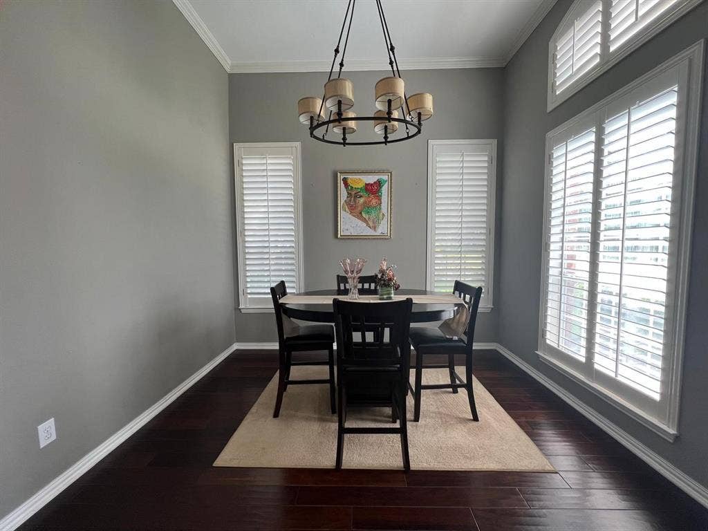 Dining space featuring dark wood-finish flooring, high ceilings, and crown molding