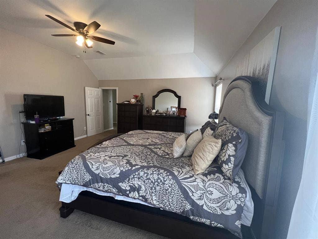Carpeted interior space featuring a vaulted ceiling and ceiling fan with integrated lighting