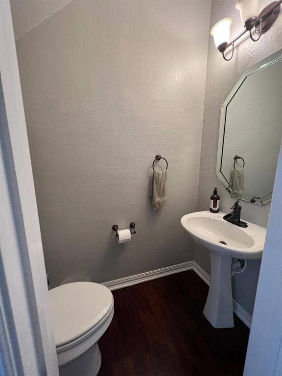 Powder room featuring a pedestal sink, an octagonal mirror, and a two-light vanity fixture