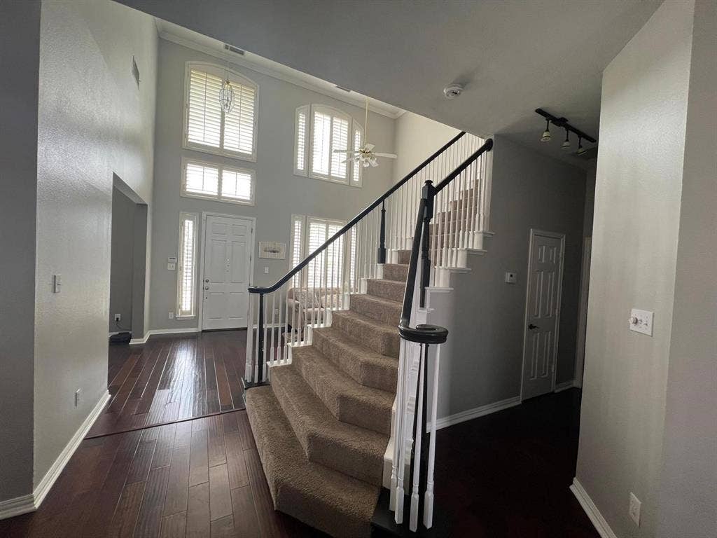 Grand two-story foyer with wood-finish flooring and a carpeted staircase